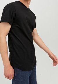 Černé tričko s krátkým rukávem vyrobené z bavlny, s kulatým lemem a klasickým designem s kulatým výstřihem. Nosit s modrými džíny.