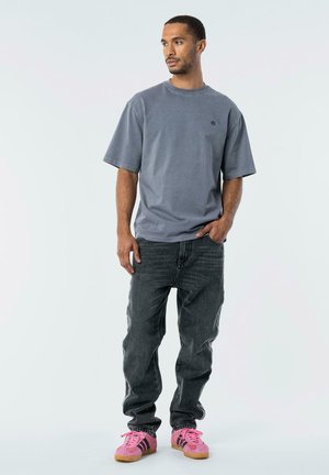 Gray oversized t-shirt, short sleeves, round neck, paired with faded black jeans and pink sneakers with black stripes. Simple design.