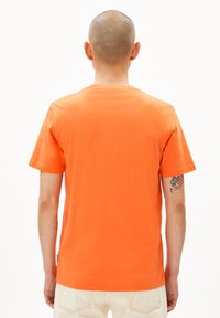 T-shirt à manches courtes en coton orange vif, avec un col rond, une texture lisse et un ourlet droit. Pas de logos de marque ou de motifs visibles.