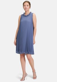 Robe sans manches bleu plissée avec un décolleté en scallop et un ourlet évasé. Fabriquée en tissu léger, elle présente un design élégant et fluide.