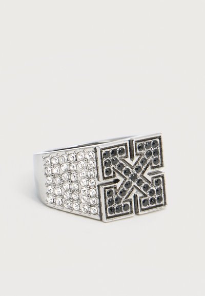 Ασημένιο δαχτυλίδι με τετράγωνο πάνω μέρος που διαθέτει μαύρο σχέδιο σε μορφή σταυρού με βέλη και πλευρές διακοσμημένες με πολλούς διάφανους στρας.