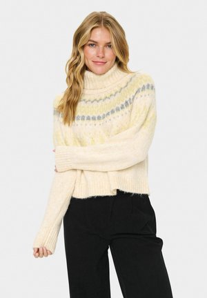 Cream-colored cropped sweater with a high turtleneck, featuring a textured pattern of yellow and gray stripes. Soft, thick knit fabric.