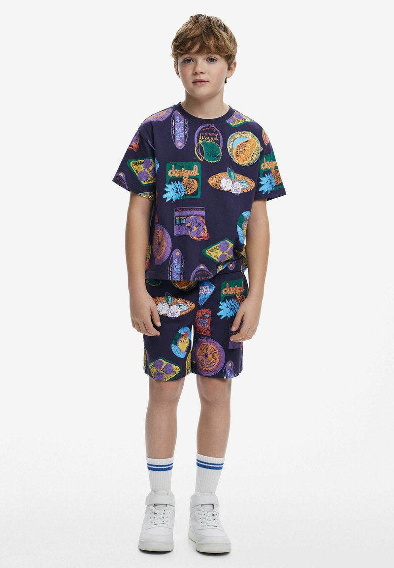 Completo con maglietta corta viola e pantaloni shorts, caratterizzato da stampe grafiche colorate. Realizzato in tessuto morbido, con un fit rilassato e life elasticizzato.