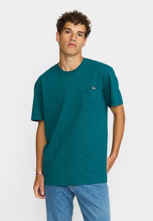 Teal katoenen t-shirt met een ronde hals, korte mouwen en een borstzakje. Gecombineerd met een klein meerkleurig logo boven de zak.