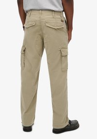 Beige cargobroek met meerdere zijzakken, een relaxte pasvorm en een gestructureerde katoen stof. Achterzakken hebben klepsluitingen.