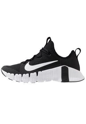 Sort-hvid Nike sportssko med mesh-overdel, hvid sål med segmenterede riller og en stor hvid Nike-swoosh på siden.