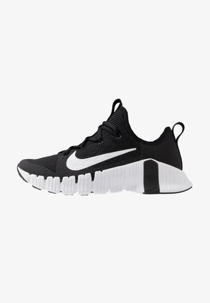 Chaussure de sport Nike noire et blanche avec empeigne en mesh, semelle blanche avec rainures segmentées, et un grand swoosh blanc Nike sur le côté.