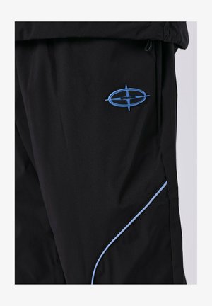 Pantalones negros hechos de un tejido ligero, con un logo azul y un ribete azul a lo largo de las costuras laterales. Textura suave, diseño moderno.