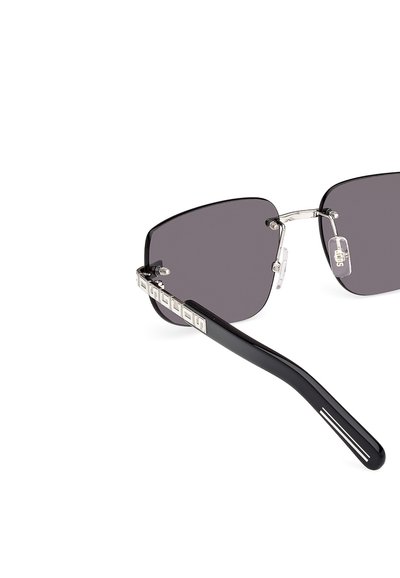 Occhiali da sole neri con montatura squadrata, lenti grigie, dettagli in metallo argento e un braccio laterale con marchio caratterizzato da un motivo ripetuto.