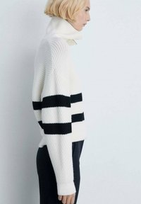 Kuscheliger Strickpullover in Weiß mit schwarzen horizontalen Streifen. Besitzt einen hohen Kragen, eine gerippte Textur und eine lockere Passform. Weiches Material.