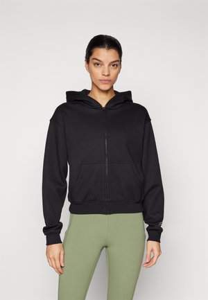 Black zip-up hoodie with a fitted design, large front pockets, and a hood. The fabric has a soft texture, complemented by ribbed cuffs.
