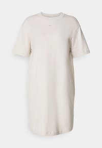 Vestido de camiseta beige claro hecho de algodón, con escote redondo, mangas cortas y un pequeño logo de Nike en el pecho.