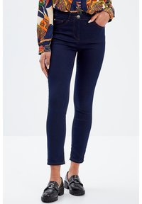 Jeans skinny blu scuro con vita alta, dotati di chiusura anteriore con bottone, due tasche posteriori e dettagli di cucitura discreti lungo le cuciture.