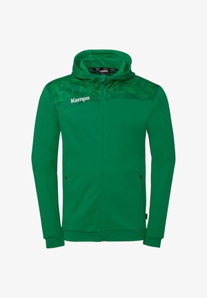Veste à capuche zippée verte avec motif géométrique sur les épaules et logo blanc "Kempa" sur le côté gauche de la poitrine.