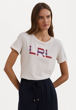 Bílý bavlněný tričko s ohrnutými rukávy, se vzorováním v mnoha barvách "LRL". Měkká textura, volný střih, kombinováno s tmavými kalhotami.