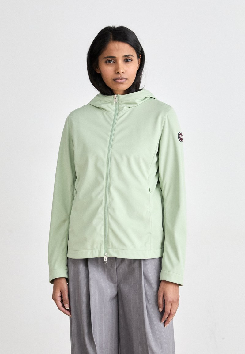 Világos zöld kapucnis dzseki elől cipzárral, oldalsó zsebekkel és logóval ellátott folttal az ujjon. Puha, sima anyag, testre szabott kialakítással.