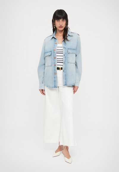 Τζιν μπουφάν σε ανοιχτό μπλε, με δύο τσέπες στο στήθος και πορτοκαλί κουμπιά. Συνοδεύεται από ριγέ μπλουζάκι και λευκό παντελόνι με φαρδιά πόδια.