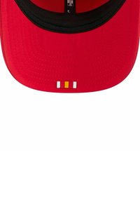Rote Mütze mit einem schwarzen Schirm, auf der Vorderseite mit einem kleinen Emblem aus drei horizontalen Streifen (weiß, gelb und weiß) versehen.