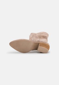 Beżowe zamszowe botki za kostkę z drewnianym, wsuwanym obcasem i teksturowaną gumową podeszwą, z okrągłym noskiem i gładkim designem cholewki.