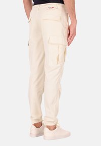 Beige cargobroek met meerdere zijzakken en een ontspannen pasvorm. Gemaakt van zachte, lichtgewicht stof. Voorzien van een logotag op de achterste tailleband.