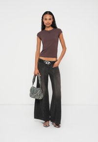 Καφέ εφαρμοστό τοπ με κοντά μανίκια, γκρι τζιν φαρδιάς γραμμής, ασημένια ζώνη με οβάλ πόρπη, γκρι τσάντα με σχέδιο και διαφανή σανδάλια με τακούνι.