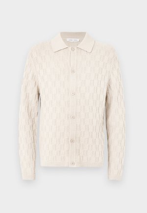 Auku džemperis off-white krāsā ar teksturētu rakstu, ar pogu priekšpusi un plakanu apkakli, garām piedurknēm ar ribotām maliņām.