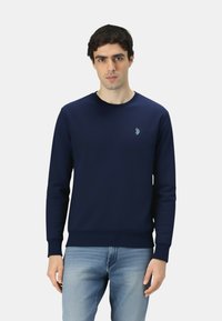 Felpa blu navy in un tessuto a trama morbida, con scollo rotondo e polsini a costine. Piccolo logo ricamato sul petto.