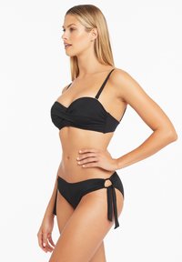 Czarny zestaw bikini z marszczonym topem bandeau z regulowanymi ramiączkami oraz dopasowanymi majtkami z wiązaniem po boku i okrągłym wycięciem.