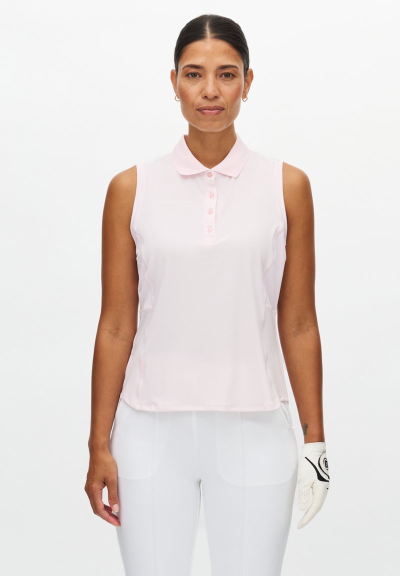 Polo senza maniche di colore rosa chiaro con collo, caratterizzata da una pattina con bottoni e tessuto liscio. Indossata con pantaloni bianchi e un guanto da golf bianco.