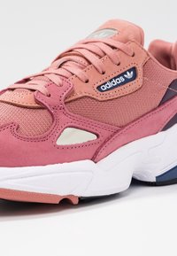 Rosa mocka och mesh sneaker med texturerade detaljer, snörning, Adidas-logotyp och vit gummisula med marinblå detaljer.