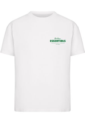 T-shirt blanc à manches courtes et col rond avec le texte vert « Matcha ESSENTIALS » et une petite phrase en dessous, sur la partie gauche de la poitrine.