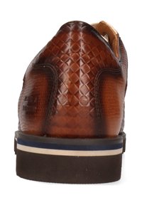 Braunes Lederschuh mit einem strukturierten, schuppenartigen Muster. Verfügt über eine flache Sohle mit blauen und beigen Streifen sowie einem abgerundeten Absatz.
