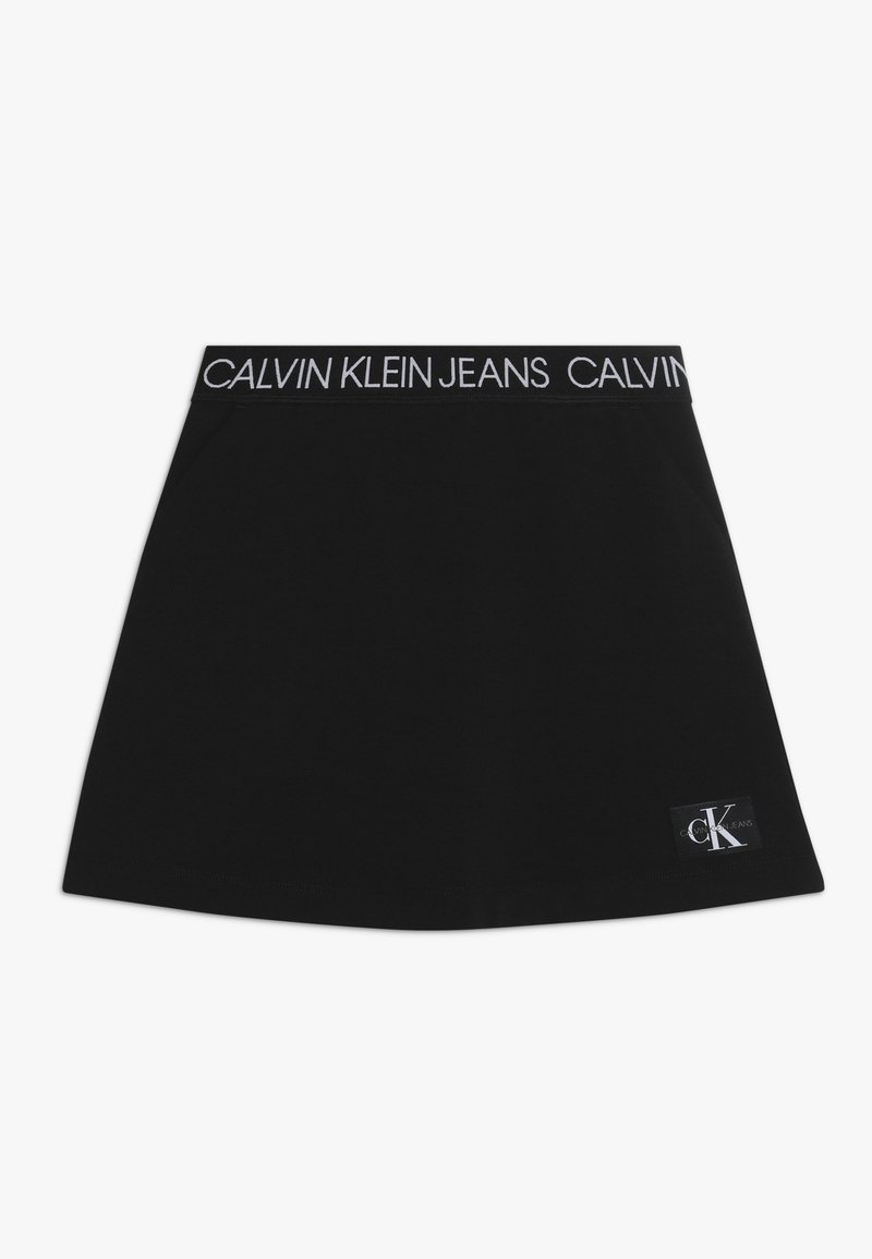 Jupe en coton noir avec une large ceinture élastique portant l'inscription "CALVIN KLEIN JEANS" et un petit patch logo sur l'ourlet.