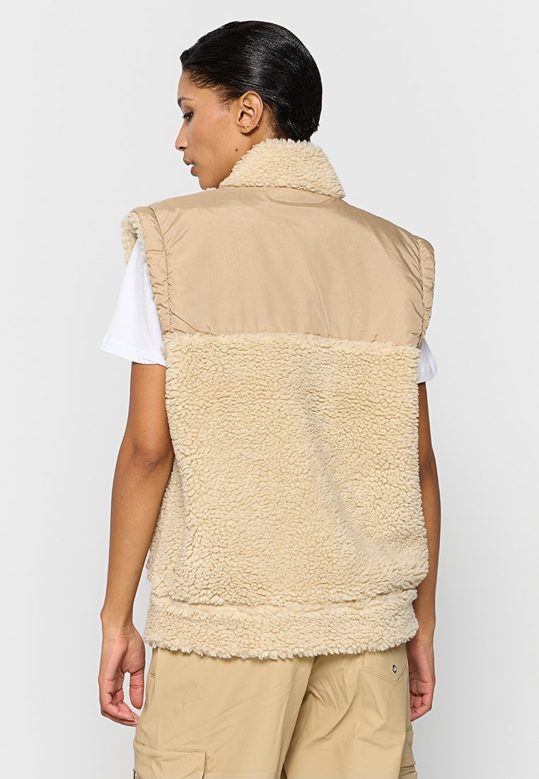 Gilet beige senza maniche con retro cremoso e texturizzato e davanti liscio color tan. Presenta un colletto alto e una vestibilità comoda.