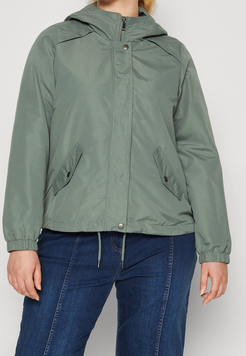 Light green lightweight jacket with a hood, zip closure, two side pockets, and elastic cuffs. Smooth texture and casual fit.