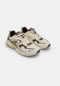 Scarpe da corsa leggere in crema, con accenti marroni, tomaia in rete, suola ammortizzata e suola in gomma testurizzata per una maggiore aderenza.