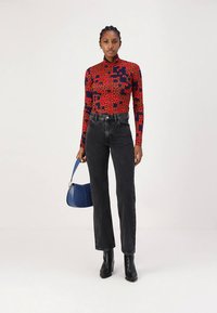 Punane ja tumesinine lillemustriga pikkade varrukatega top, kõrge vöökohaga mustad teksad, mustad pahkluu saapad ning sinine käekott. Sile tekstuur ja kehakuju rõhutav lõige.