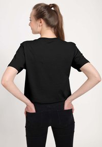 T-shirt nera a maniche corte con scollatura rotonda classica, realizzata in tessuto di cotone liscio. Stilizzata con una vestibilità comoda e senza motivi distintivi.