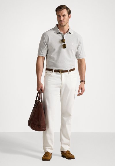 Sivina polo majica, bele hlače in rjavi usnjeni čevlji. Drži rjavo usnjeno torbo, s sončnimi očali na majici. Obleka za prosti čas.