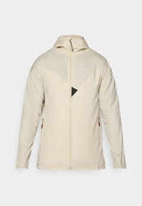 Beige, lightweight jacket with long sleeves, zip closure, adjustable hood, and a triangular black accent on the chest. Features side zip pockets.