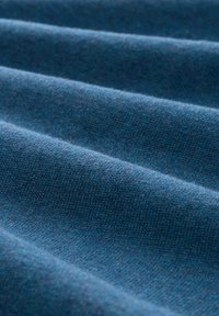 Material albastru cu o textură moale și un model subtire în dungi, având pliuri diagonale ce creează adâncime și dimensiune în aspect.