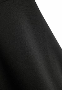 Schwarzer Stoff mit glatter Textur, der einen leichten Glanz aufweist. Das Material sieht dehnbar und leicht schimmernd aus, wenn man es aus der Nähe betrachtet.