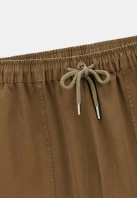 Shorts marron à cordon de serrage fabriqués en tissu doux avec une finition texturée. Présentent une taille élastique, un détail de bouton et un cordon de serrage noué.