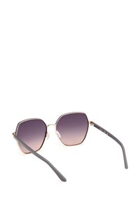 Hexagonální sluneční brýle s gradientními fialovými čočkami, tenkým zlatým kovovým rámem a šedými plastovými stranami. Průhledné nosní podložky pro pohodlí.