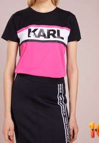 Black and pink T-shirt with a white stripe, featuring "KARL" in bold black letters. Soft fabric, relaxed fit, paired with a black skirt.