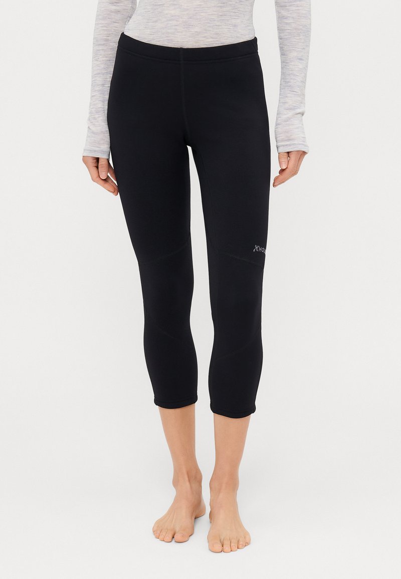 Leggings capri neri realizzati in materiale elastico, con una cintura elastica, dettagli cuciti e un logo sulla parte inferiore della gamba sinistra.