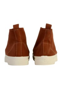 Bruine canvas hoge schoenen met een witte rubberen zool, voorzien van stiksels en trekentorens op de hiel voor eenvoudig aantrekken.