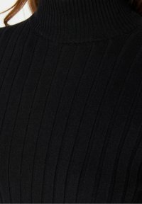 Schwarzer gerippter Rollkragenpullover mit dichtem Strickmuster und taillierter Passform, der vertikale Streifen aufweist.