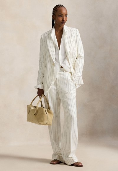 Λευκό ριγέ κοστούμι με παντελόνι φαρδιάς γραμμής και σακάκι ραμμένο στα μέτρα, συνδυασμένο με λευκό πουκάμισο σε άνετη γραμμή και μπεζ τσάντα. Υφή υφάσματος και εφαρμογή.
