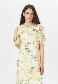 Rochie florală dintr-un material ușor, cu lămâi galbene și frunze verzi. Mâneci puff structurate, decolteu rotund, design până la genunchi.
